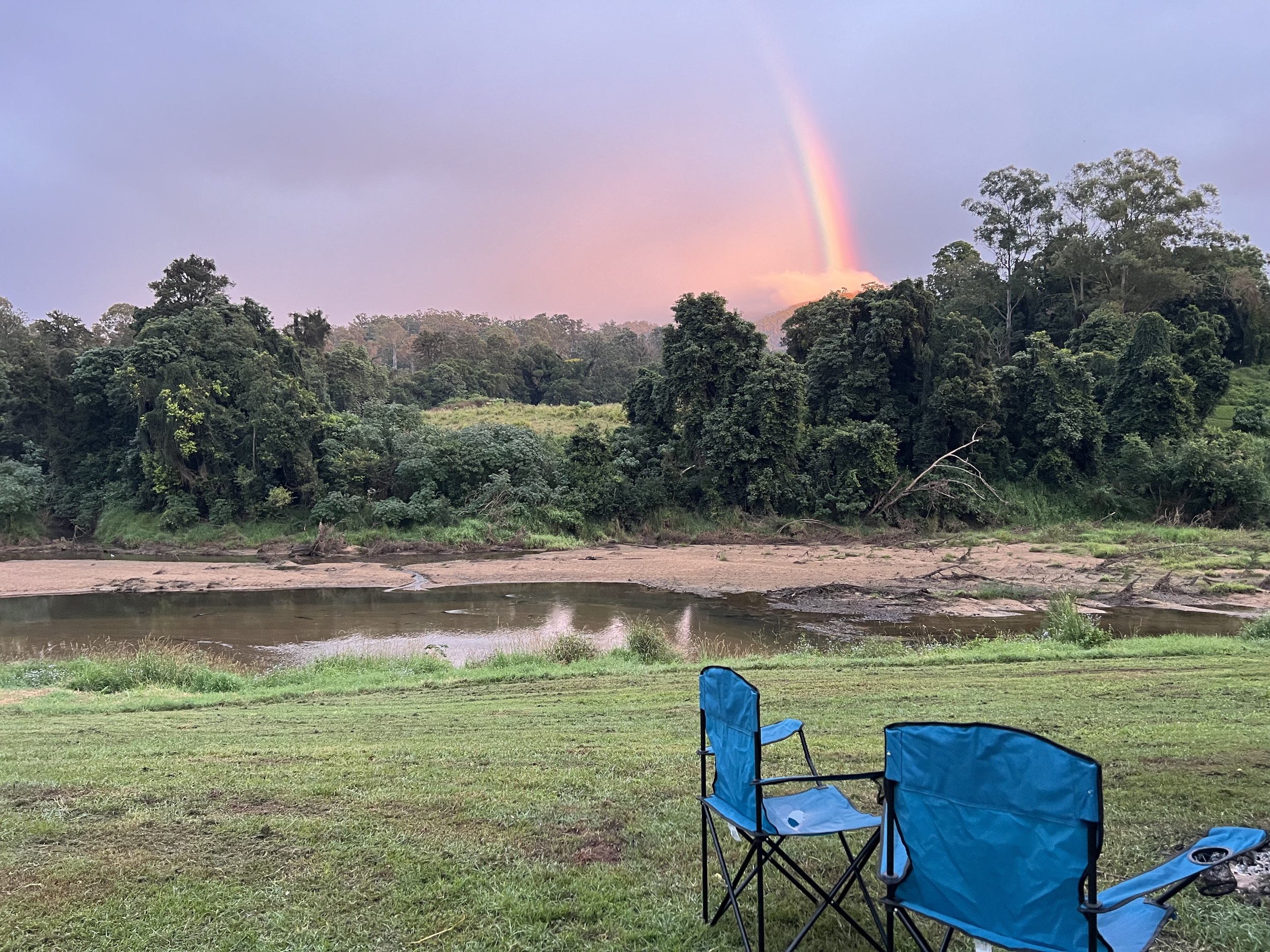 A rainbow behind the Mary River with 2 camp chairs on Kenilworth Camping on the River campsite